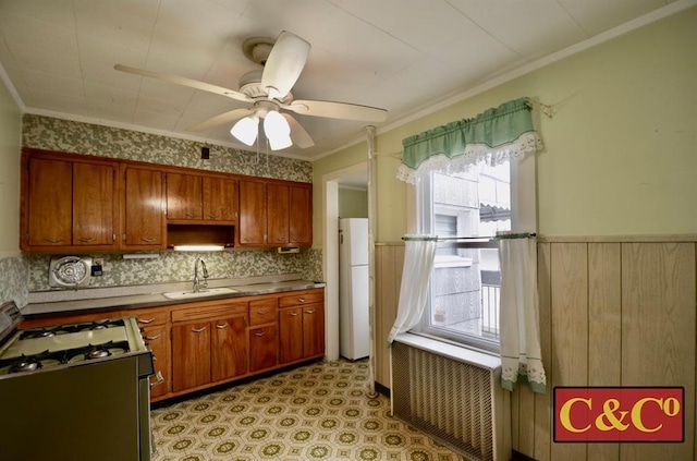 1927 E 34th St, Brooklyn, NY 11234 - kitchen with white appliances, a sink, brown cabinets, a ceiling fan, and wainscoting