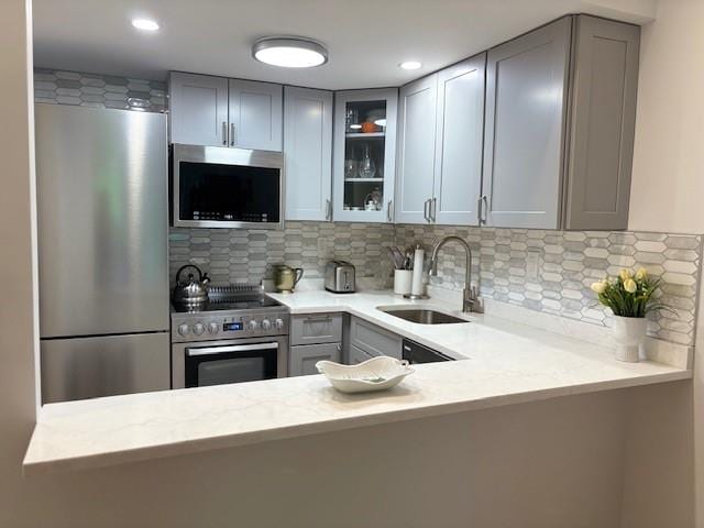9977 Shore Rd Unit 11C, Brooklyn, NY 11209 - kitchen with appliances with stainless steel finishes, gray cabinetry, glass insert cabinets, decorative backsplash, and recessed lighting
