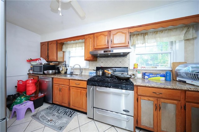 50 Glenwood Ave, Staten Island, NY 10301 - kitchen featuring under cabinet range hood, appliances with stainless steel finishes, brown cabinetry, decorative backsplash, and light tile patterned floors