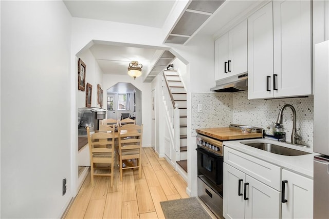 880 Bay Ridge Ave, Brooklyn, NY 11220 - kitchen with under cabinet range hood, black electric range, arched walkways, a sink, and tasteful backsplash