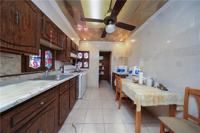 8669 15th Ave, Brooklyn, NY 11228 - kitchen featuring white range with gas cooktop, under cabinet range hood, light countertops, ceiling fan, and light tile patterned floors