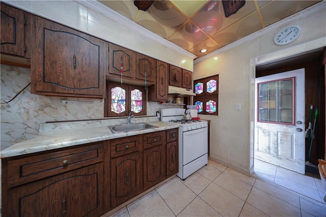8669 15th Ave, Brooklyn, NY 11228 - kitchen featuring white gas range oven, under cabinet range hood, light tile patterned floors, tasteful backsplash, and dark brown cabinets