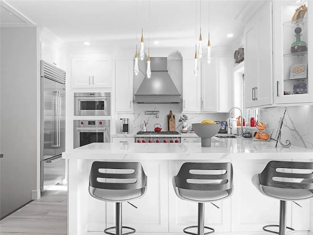 4906 21st Ave, East Elmhurst, NY 11370 - kitchen featuring wall chimney range hood, stainless steel appliances, a peninsula, white cabinets, and decorative backsplash
