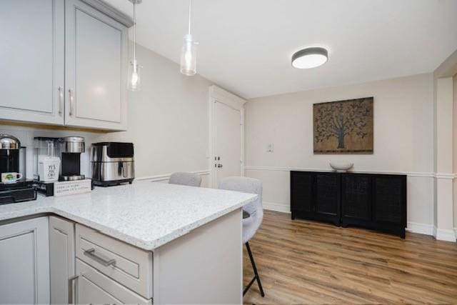 400 Maryland Ave Unit 2D, Staten Island, NY 10305 - kitchen with light wood-style floors, a kitchen bar, a peninsula, white cabinetry, and hanging light fixtures