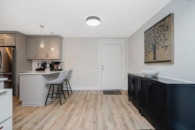 400 Maryland Ave Unit 2D, Staten Island, NY 10305 - kitchen with freestanding refrigerator, a breakfast bar area, light countertops, light wood-style flooring, and pendant lighting