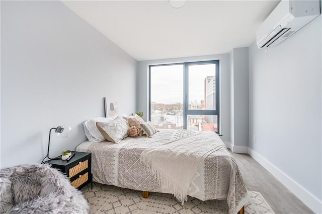 811 45th St Unit 5B, Brooklyn, NY 11220 - bedroom featuring a wall unit AC, light wood-style flooring, and baseboards
