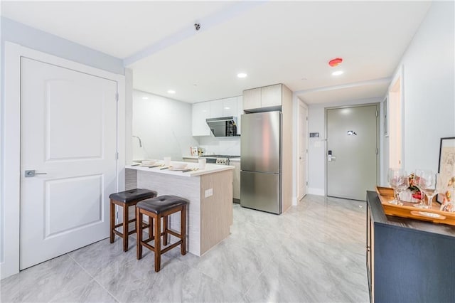 811 45th St Unit 5B, Brooklyn, NY 11220 - kitchen with stainless steel appliances, a kitchen breakfast bar, white cabinetry, modern cabinets, and a peninsula