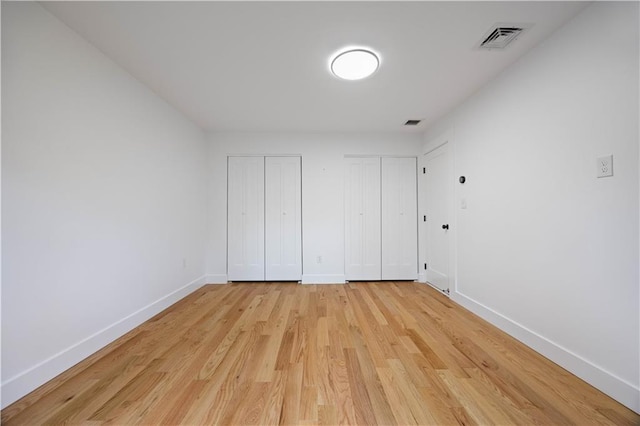 164 Railroad St, Staten Island, NY 10312 - unfurnished bedroom featuring two closets, baseboards, and light wood-style floors