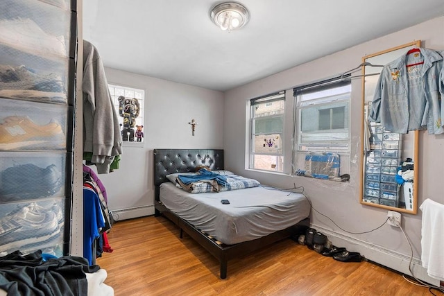 32 Brighton 2nd Pl, Brooklyn, NY 11235 - bedroom with light wood-type flooring, multiple windows, and a baseboard heating unit