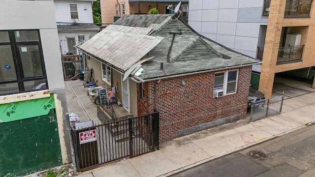 32 Brighton 2nd Pl, Brooklyn, NY 11235 - view of property exterior with brick siding, a fenced front yard, a gate, and a shingled roof
