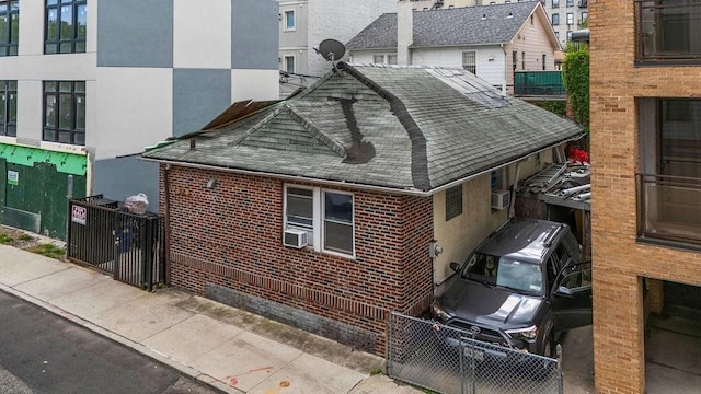32 Brighton 2nd Pl, Brooklyn, NY 11235 - view of home's exterior with a shingled roof, brick siding, and cooling unit