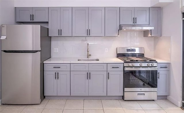 1745 E 21st St, Brooklyn, NY 11229 - kitchen with stainless steel appliances, gray cabinets, under cabinet range hood, backsplash, and light tile patterned floors
