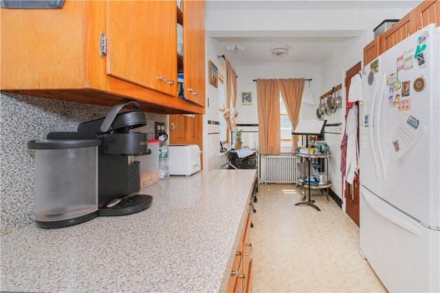 4070 Victory Blvd, Staten Island, NY 10314 - kitchen featuring freestanding refrigerator, radiator, light countertops, and brown cabinetry