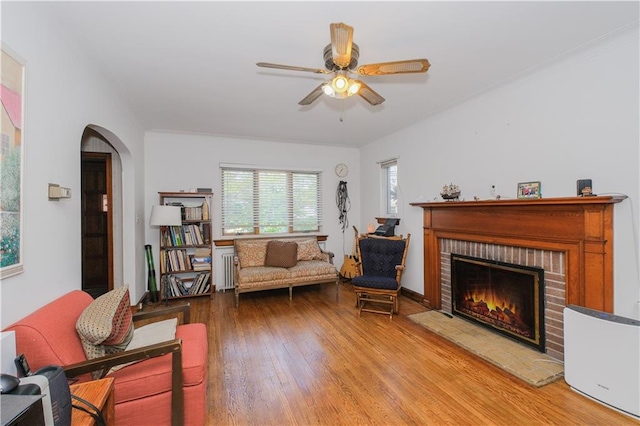4070 Victory Blvd, Staten Island, NY 10314 - living room with wood finished floors, ceiling fan, a fireplace, arched walkways, and radiator