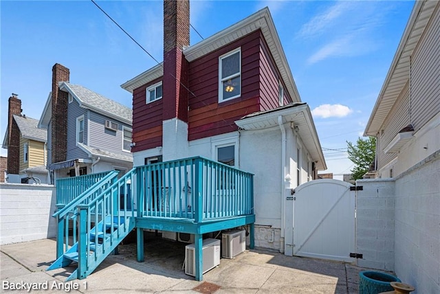 2160 E 36th St, Brooklyn, NY 11234 - back of house featuring a gate, a chimney, a deck, a garage, and concrete driveway