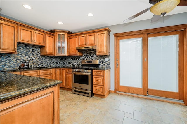 61 Avon Ln, Staten Island, NY 10314 - kitchen with stainless steel gas range, under cabinet range hood, brown cabinets, backsplash, and stone tile floors
