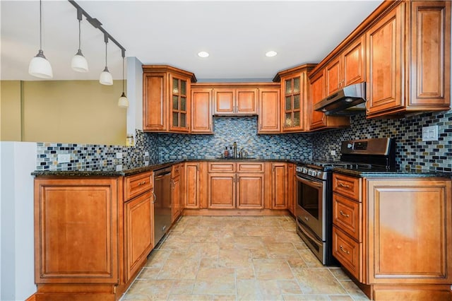 61 Avon Ln, Staten Island, NY 10314 - kitchen with appliances with stainless steel finishes, under cabinet range hood, brown cabinets, a peninsula, and dark stone counters