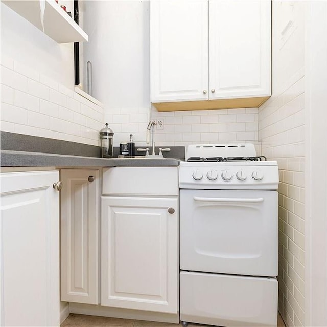 41 Jane St Unit 5B, New York, NY 10014 - kitchen with gas range gas stove, dark countertops, white cabinetry, and tasteful backsplash