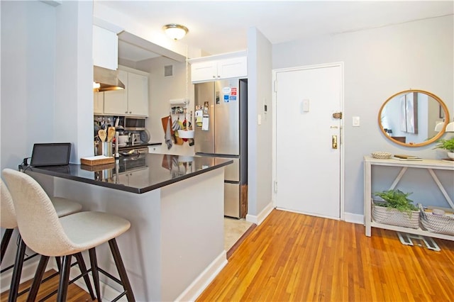 9323 Shore Rd Unit 4G, Brooklyn, NY 11209 - kitchen with freestanding refrigerator, dark countertops, a kitchen breakfast bar, white cabinetry, and a peninsula