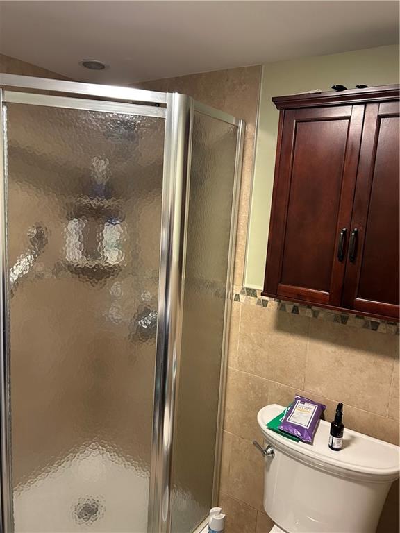 30 Regis Dr Unit 76, Staten Island, NY 10314 - bathroom with a stall shower, tile walls, and wainscoting