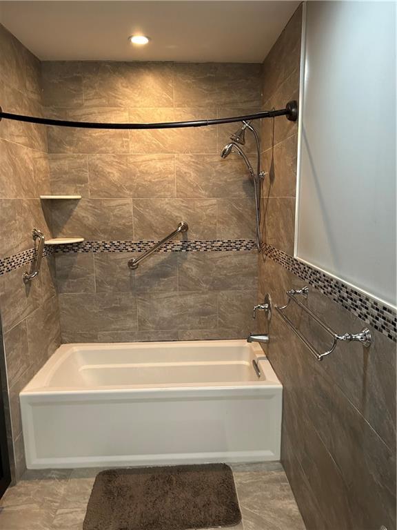 30 Regis Dr Unit 76, Staten Island, NY 10314 - bathroom featuring tile walls, washtub / shower combination, and tile patterned flooring
