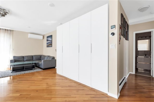 135 28th Ave Unit 2A, Brooklyn, NY 11214 - living room featuring an AC wall unit, light wood-style flooring, and baseboard heating