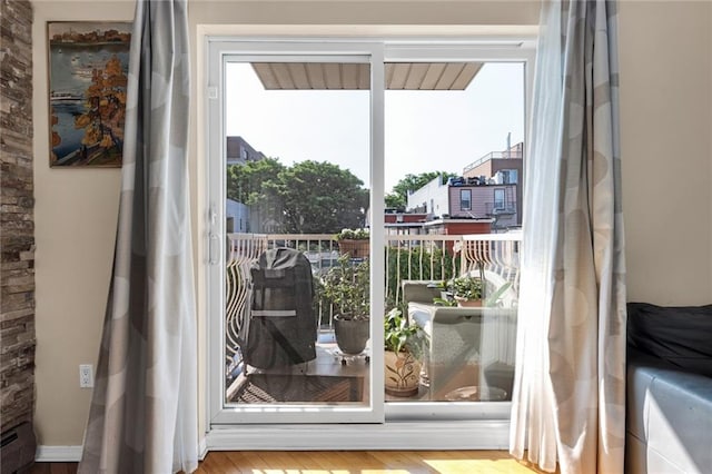 135 28th Ave Unit 2A, Brooklyn, NY 11214 - doorway to outside with healthy amount of natural light, wood finished floors, and a baseboard radiator