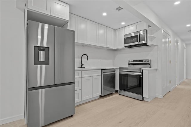 320 10th St, Brooklyn, NY 11215 - kitchen featuring appliances with stainless steel finishes, light countertops, light wood-type flooring, white cabinets, and recessed lighting