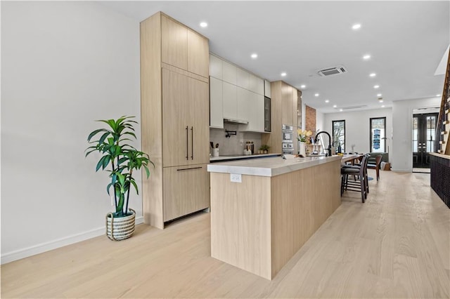 320 10th St, Brooklyn, NY 11215 - kitchen featuring modern cabinets, an island with sink, light wood-style floors, light brown cabinetry, and recessed lighting