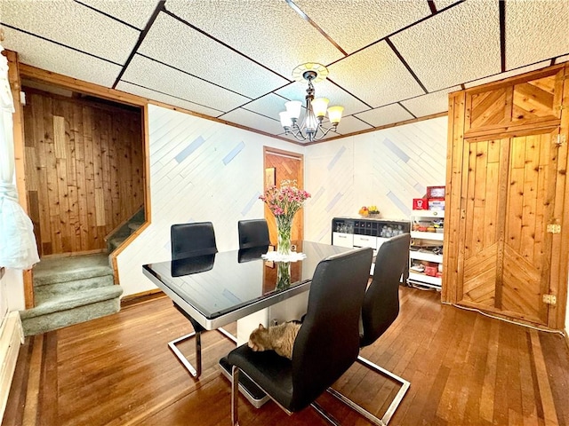 3516 Fillmore Ave, Brooklyn, NY 11234 - dining room featuring hardwood / wood-style floors, a chandelier, stairs, wood walls, and a paneled ceiling