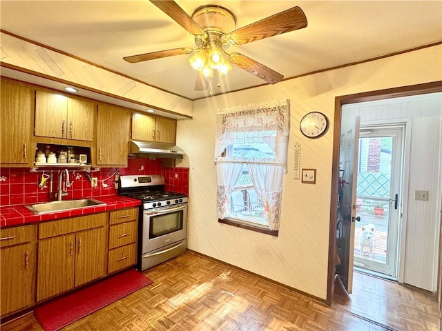 3516 Fillmore Ave, Brooklyn, NY 11234 - kitchen with stainless steel gas range, under cabinet range hood, tile countertops, brown cabinets, and backsplash