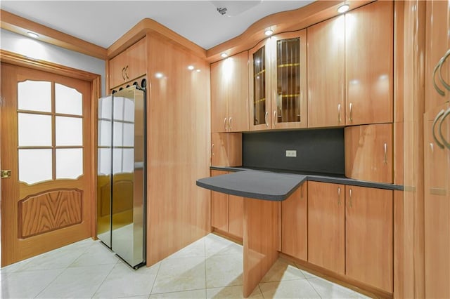 35 Seacoast Ter Unit 8A, Brooklyn, NY 11235 - kitchen with refrigerator, dark countertops, glass insert cabinets, light tile patterned floors, and a peninsula