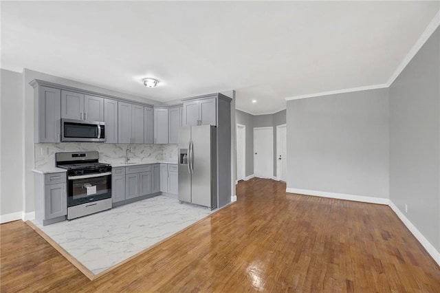 1650 E 48th St, Brooklyn, NY 11234 - kitchen featuring appliances with stainless steel finishes, gray cabinetry, crown molding, decorative backsplash, and light wood-style floors