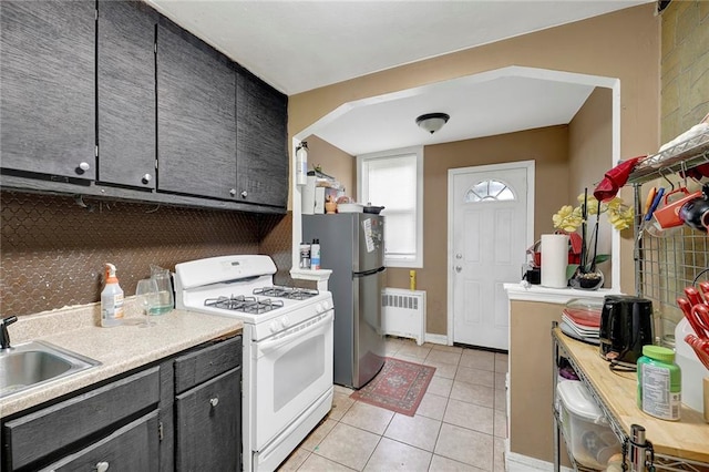 1650 E 48th St, Brooklyn, NY 11234 - kitchen featuring white gas range oven, radiator heating unit, light tile patterned flooring, freestanding refrigerator, and light countertops
