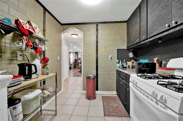 1650 E 48th St, Brooklyn, NY 11234 - kitchen featuring white gas range, light tile patterned flooring, arched walkways, crown molding, and light countertops