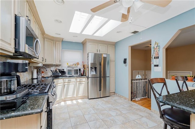 731 Stafford Ave, Staten Island, NY 10309 - kitchen with stainless steel appliances, tasteful backsplash, a ceiling fan, a skylight, and dark stone counters