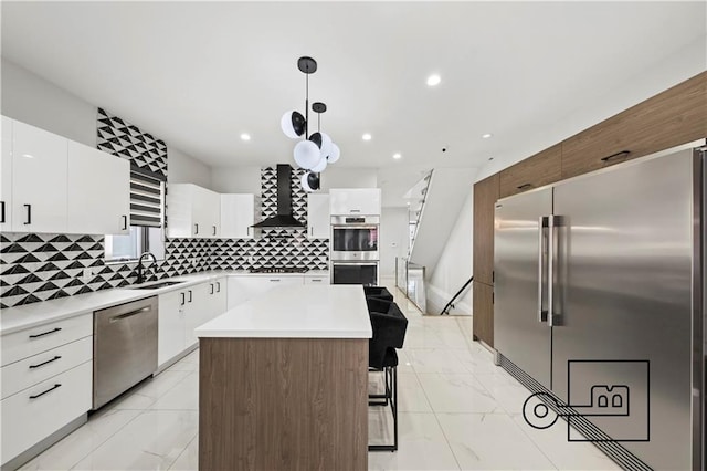1168 E 12th St, Brooklyn, NY 11230 - kitchen with appliances with stainless steel finishes, wall chimney exhaust hood, light marble finish floors, a breakfast bar area, and recessed lighting