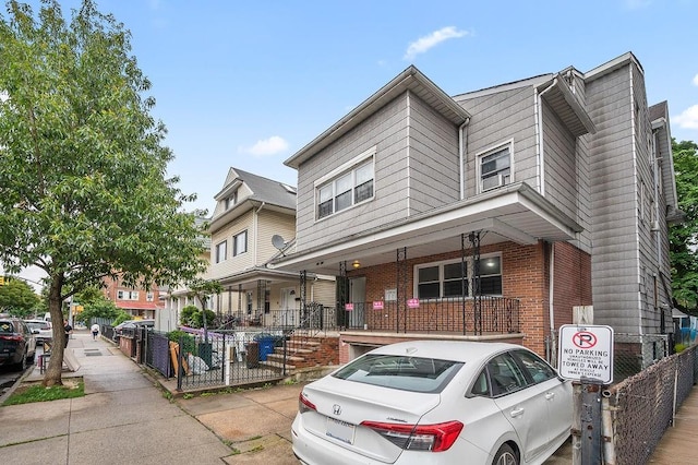 8309 19th Ave, Brooklyn, NY 11214 - view of property with a porch, a fenced front yard, and brick siding