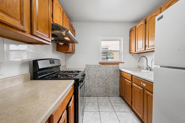 8309 19th Ave, Brooklyn, NY 11214 - kitchen with freestanding refrigerator, stainless steel range with gas stovetop, under cabinet range hood, and light countertops