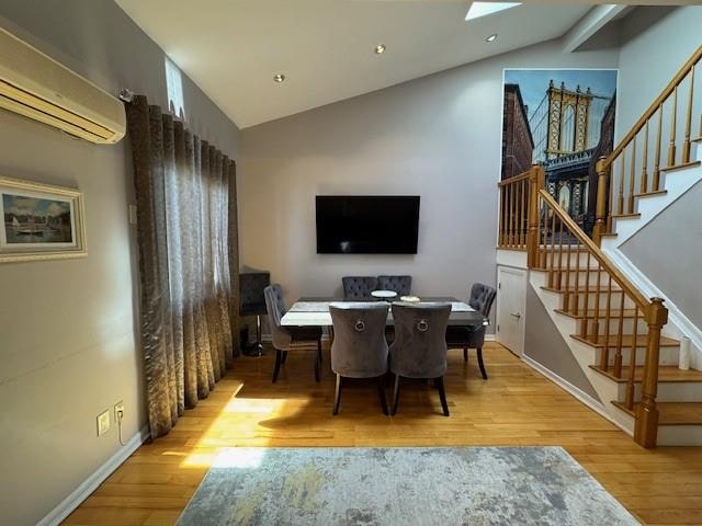 3541 Shore Pkwy Unit B2, Sheepshead Bay, NY 11235 - dining space featuring vaulted ceiling, an AC wall unit, wood finished floors, and stairs