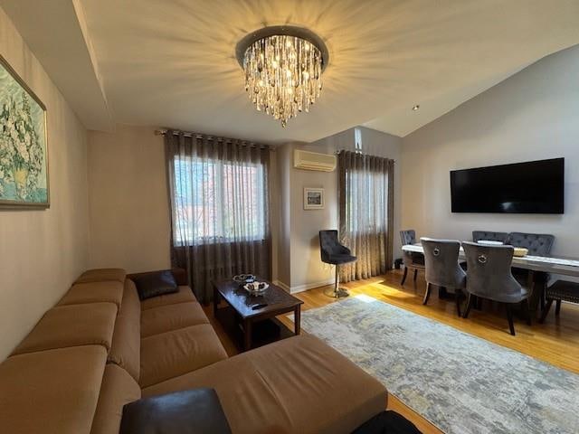 3541 Shore Pkwy Unit B2, Sheepshead Bay, NY 11235 - living area with a wall mounted AC, wood finished floors, lofted ceiling, and a chandelier