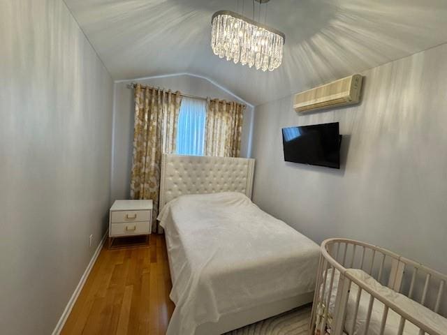 3541 Shore Pkwy Unit B2, Sheepshead Bay, NY 11235 - bedroom featuring a wall unit AC, wood finished floors, a chandelier, and lofted ceiling