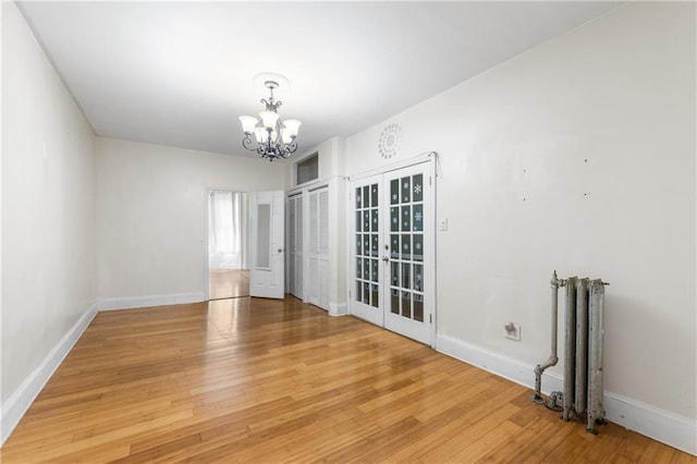 317 Pennsylvania Ave, Brooklyn, NY 11207 - empty room featuring a chandelier, radiator heating unit, light wood-type flooring, and french doors