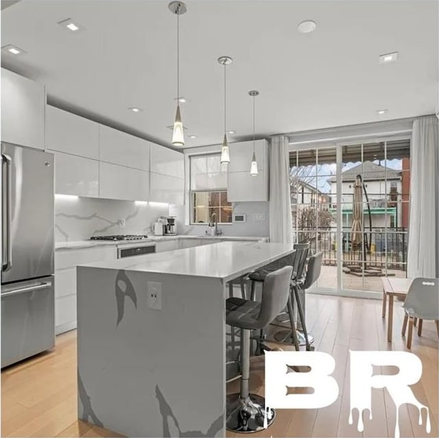 2507 E 23rd St, Brooklyn, NY 11235 - kitchen with appliances with stainless steel finishes, a kitchen bar, light wood finished floors, modern cabinets, and recessed lighting