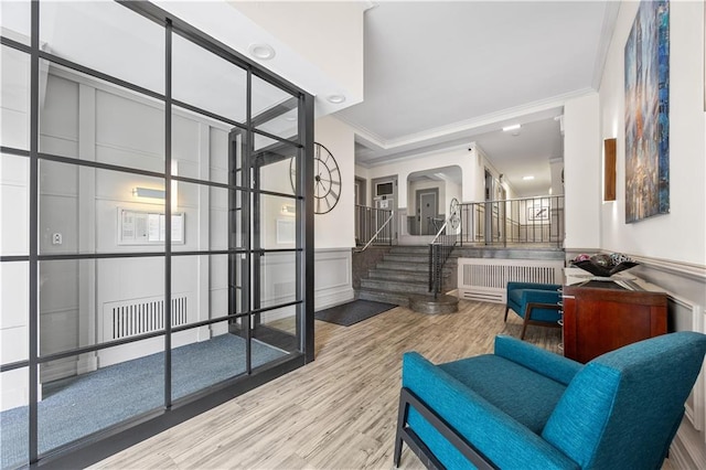 9430 Ridge Blvd Unit 4E, Brooklyn, NY 11209 - living area with radiator heating unit, ornamental molding, stairs, a decorative wall, and wood finished floors