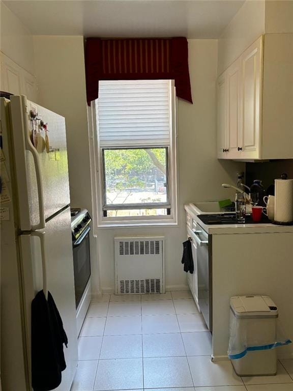 2250 Brigham St Unit 3C, Brooklyn, NY 11229 - kitchen featuring white appliances, radiator heating unit, white cabinetry, and light tile patterned floors