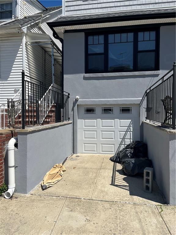 1661 W 5th St, Brooklyn, NY 11223 - view of property exterior featuring a garage, stairway, and stucco siding