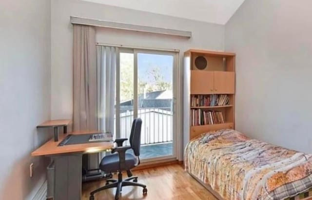 4817 Bedford Ave Unit 3A, Brooklyn, NY 11235 - bedroom featuring wood finished floors, access to exterior, an office area, and vaulted ceiling