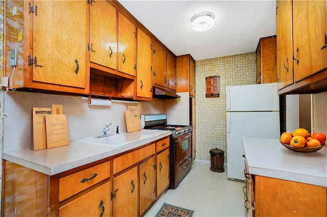 1935 Shore Pkwy Unit 8E, Brooklyn, NY 11214 - kitchen featuring gas stove, freestanding refrigerator, under cabinet range hood, brown cabinets, and light countertops