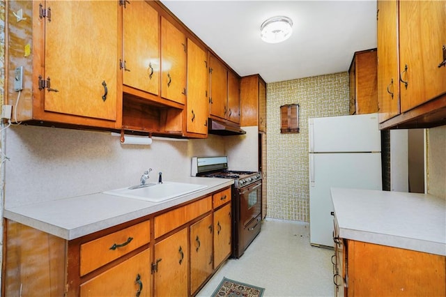 1935 Shore Pkwy Unit 8E, Brooklyn, NY 11214 - kitchen with range with gas stovetop, freestanding refrigerator, under cabinet range hood, brown cabinetry, and light countertops